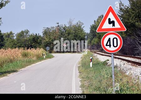 Segnale di avvertenza che mostra una freccia piegata che avvisa il conducente in avvicinamento a doppia curva su strada con segnale di velocità massima 40 Foto Stock