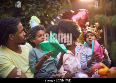 la famiglia afro-americana si è riunita in festa di compleanno giocando insieme alla carta cappello e barche Foto Stock