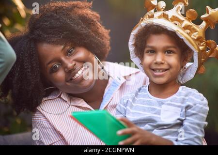 la bambina afro-americana e la mamma sorridono insieme, guardando la macchina fotografica. contatto con gli occhi Foto Stock