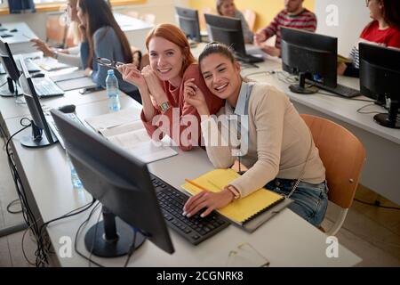 Le studentesse sorridono e posano ad una lezione di informatica la classe informatica dell'università Foto Stock