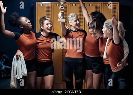 Una squadra femminile in un armadietto entusiasta del vinto tazza Foto Stock