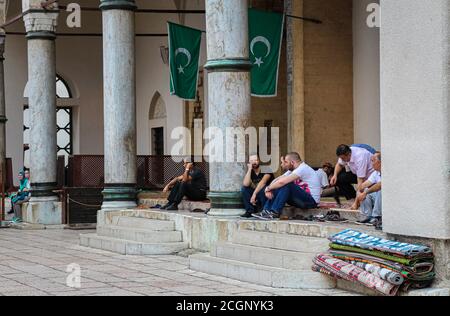 Sarajevo, Bosnia-Erzegovina - 3 luglio 2018: Musulmani seduti fuori dalla Moschea Madrasa di Gazi Husrev-Beg, nel quartiere Bascarsija, città vecchia Foto Stock