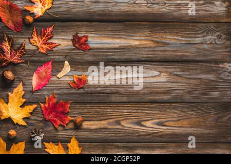 Composizione autunnale fatta di foglie autunnali, fiori, noci, coni di pino su rustico sfondo di legno. Disposizione piatta, vista dall'alto con spazio per la copia Foto Stock