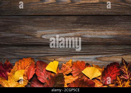 Composizione autunnale fatta di foglie d'autunno secche su sfondo rustico di legno. Disposizione piatta, vista dall'alto con spazio per la copia Foto Stock