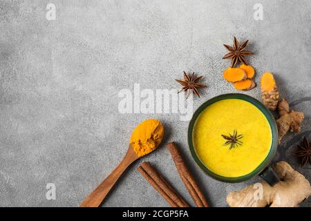 Bevanda curcuma, latte, tè, latte dorato con cannella, zenzero e anice in una tazza su fondo di cemento. Vista dall'alto con spazio per la copia Foto Stock