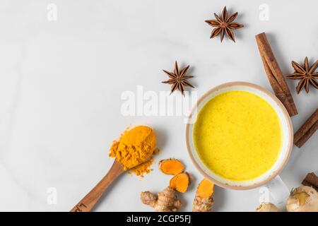 Bevanda curcuma, latte, tè, latte dorato con cannella, zenzero e anice in una tazza su sfondo bianco. Vista dall'alto con spazio per la copia Foto Stock