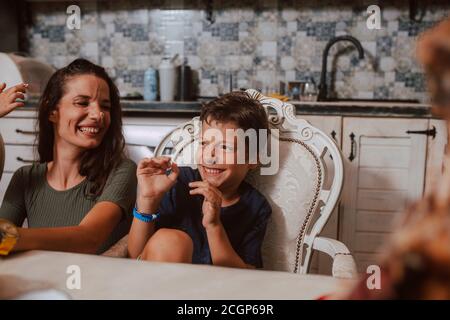 Una bella madre caucasica e due figli sono cosparsi di crema di cioccolato sul viso. Divertimento con i bambini Foto Stock