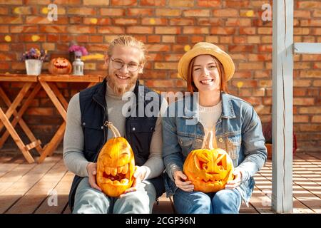 Concetto di preparazione di Halloween. Giovane coppia seduta al portico con jack-o'-lanterna sorridente felice Foto Stock