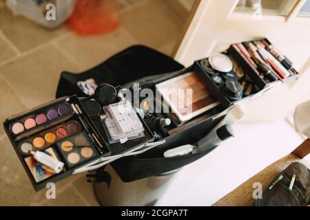 Set di artisti per il trucco. Grande borsa cosmetica aperta con ombretto, arrossamento e rossetto in una stanza luminosa. Foto Stock