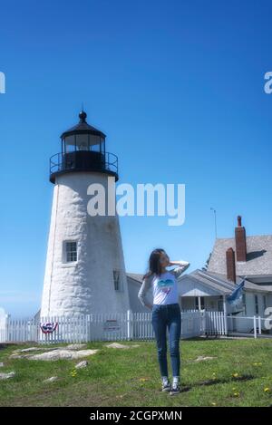 Una donna cinese che si trova vicino all'iconica casa di luce punto pemaquid a Bristol Maine in una giornata di cielo blu soleggiato con gli occhi chiusi fissando i capelli. Foto Stock