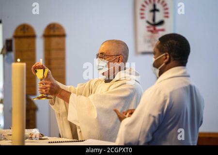 Sacerdote cattolico che prepara la Santa comunione indossando la maschera di messa Durante la pandemia di Coronavirus / Covid 19 in Inghilterra UK 2020 Foto Stock