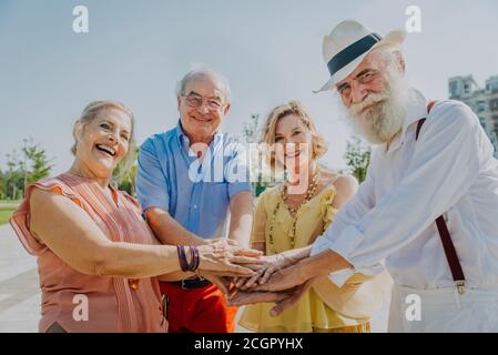 Gruppo di giovani anziani che si divertono all'aperto - quattro pensionati che si legano all'aperto, concetti di stile di vita e anziani Foto Stock