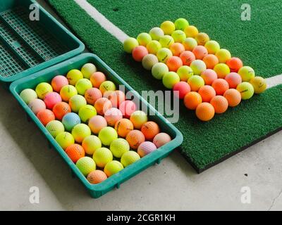 Palline da golf usate e colorate di marche assortite in un campo pratica. Foto Stock