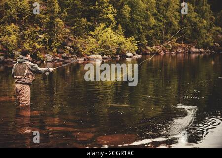 Bobina di corda da pesca del mosca, mano dell'uomo che tiene la canna Foto Stock