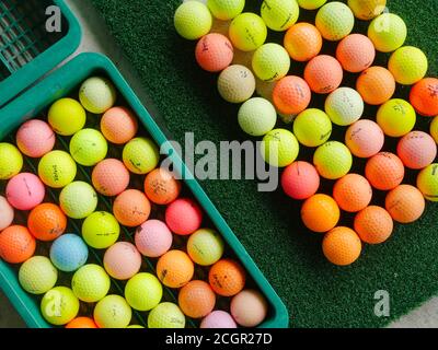 Palline da golf usate e colorate di marche assortite in un campo pratica. Foto Stock