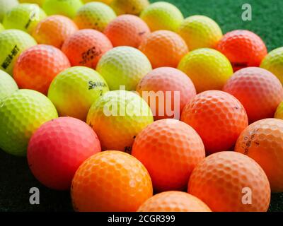 Palline da golf usate e colorate di marche assortite in un campo pratica. Foto Stock