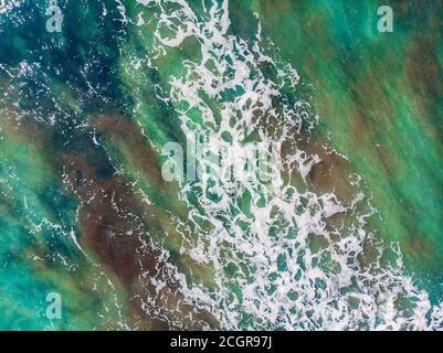 Piccole onde turchesi per il surf su scudini di mare bassa marea o riflusso, vista dall'alto aerea Foto Stock