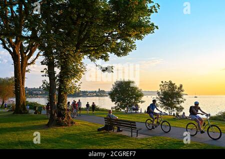Coppie giovani in bicicletta, altri a piedi o a jogging nel tardo pomeriggio e godersi il tramonto allo Stanley Park Vancouver, British Columbia, Canada Foto Stock