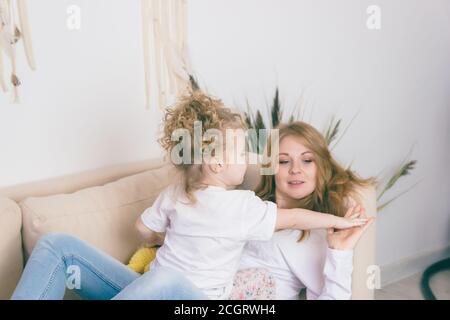 La giovane madre passa del tempo con la sua bambina che gioca sul divano. Foto Stock