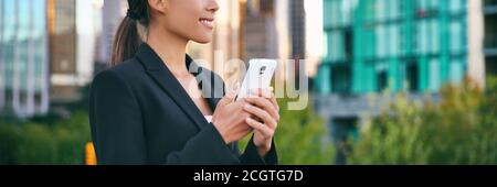 Telefono cellulare giovane donna d'affari utilizzando il cellulare testando banner panoramico. Signora che lavora in ufficio fuori dall'hotel mentre si è in viaggio per la strada della città Foto Stock