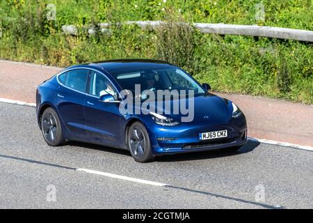 2019 blu Tesla Model EV 3 Long Range AWD; veicoli in movimento per il traffico veicolare, auto che guidano veicoli su strade del Regno Unito, motori, auto sulla rete autostradale M6. Foto Stock