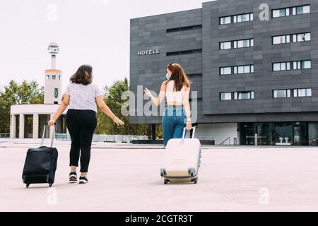 due giovani turisti che indossano maschere a piedi per il loro hotel manutenzione una distanza di sicurezza grazie alla covid-19 Foto Stock