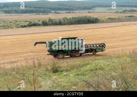 La trebbiatrice combinata si muove sul campo durante la mietitura. Foto Stock