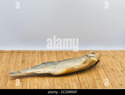 un pesce secco di ariete su uno sfondo rustico di legno closeup contro il bianco Foto Stock