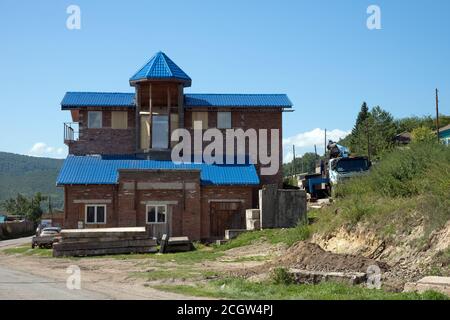 Costruzione di una casa in mattoni su una strada del villaggio in estate. Foto Stock