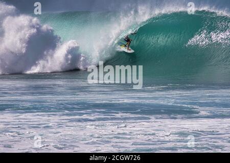 Irriconoscibile surfista profondo nel riccio di una massiccia onda della costa settentrionale di oahu. Foto Stock
