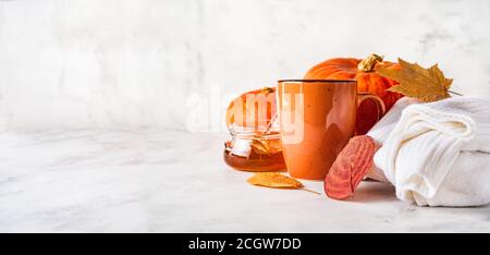 Composizione autunnale creativ con coppa d'arancia, zucca, vaso di miele, maglione caldo su sfondo bianco. Spazio di copia. Banner Foto Stock