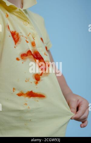 Il bambino tira una T-shirt con macchie dal ketchup Foto Stock