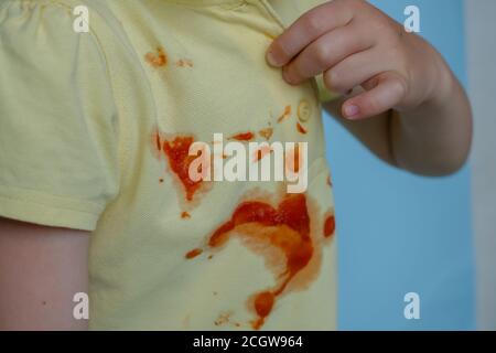 Il bambino tira una T-shirt con macchie dal ketchup Foto Stock