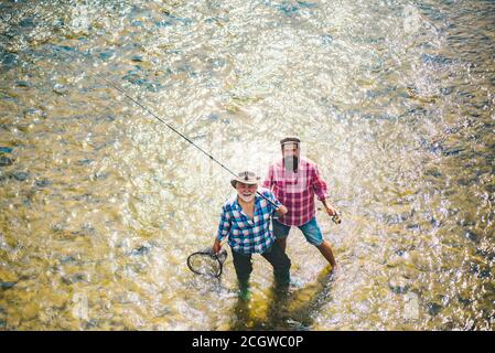 Elegante bearded uomini di pesca. Rilassatevi in un ambiente naturale. Pesca fuori limite. Felice amicizia dei pescatori. Fishman crocheted gira nel fiume Foto Stock