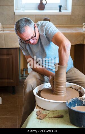 Concetto di ceramica. Ceramista professionista che lavora con creta al tavolo di lancio in officina, studio. Foto Stock