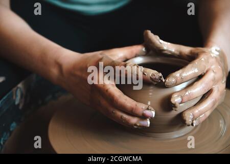 Concetto di ceramica. Ceramista professionista che lavora con creta al tavolo di lancio in officina. Foto Stock