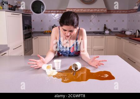Bella giovane donna che guarda perplesso a un pasticcio sul contatore Foto Stock