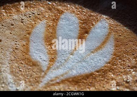 Un primo piano di un caffè latte che mostra l'arte latte e il colore ricco del latte espresso al vapore. Foto Stock
