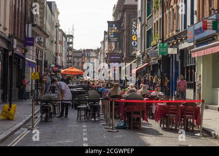 Old Compton Street a Soho con bevande e pasti all'aperto durante il giorno. Londra Foto Stock