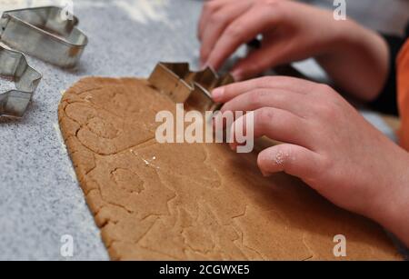 Mani di bambino usando le muffe di natale sull'impasto, immagine di closeup Foto Stock