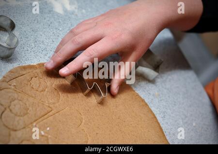 Mani di bambino usando le muffe di natale sull'impasto, immagine di closeup Foto Stock