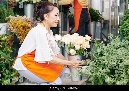 Donna che organizza fiori in negozio Foto Stock