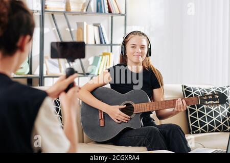 Ragazzo filmando sorella canto Foto Stock