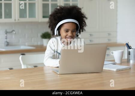 Etnia africana piccola ragazza che indossa le cuffie, guardando lo schermo del computer. Foto Stock