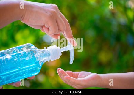 Sfondo sfocato della madre che pulisce la mano dei suoi bambini con pompa igienizzante in gel di alcool per l'igiene proteggere la chemioterapia malata debole, gli ausili, i bambini pazienti da fl Foto Stock