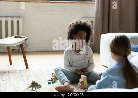 Sorridente adorabile ragazza capretto afroamericana giocando con un amico europeo. Foto Stock