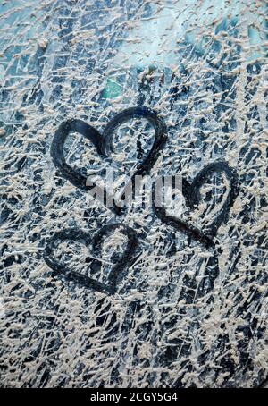 Tre cuori attirati su finestra grime strato di grigio secco fango Foto Stock