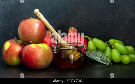 Miele, melograno e mele sulla tavola nera. Cartolina di Capodanno ebraico Rosh Hashanah. Foto Stock
