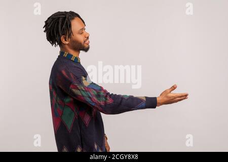 Profilo ritratto amico africano uomo con dreadlock stretching mano accogliendo gli ospiti con un sorriso toothy sul viso, Piacere di conoscerti. Riprese in studio al coperto Foto Stock