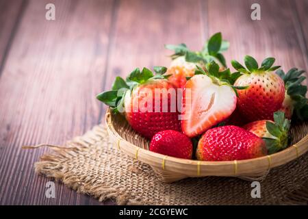 Fragola tagliata fresca in cesto di bambù su tavola di legno, Foto Stock